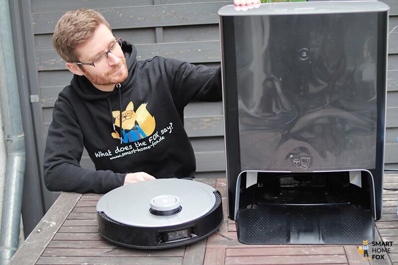 Die Multifunktionstation des Ecovacs Deebot X1 OMNI steht auf dem Tisch neben dem Saugroboter.